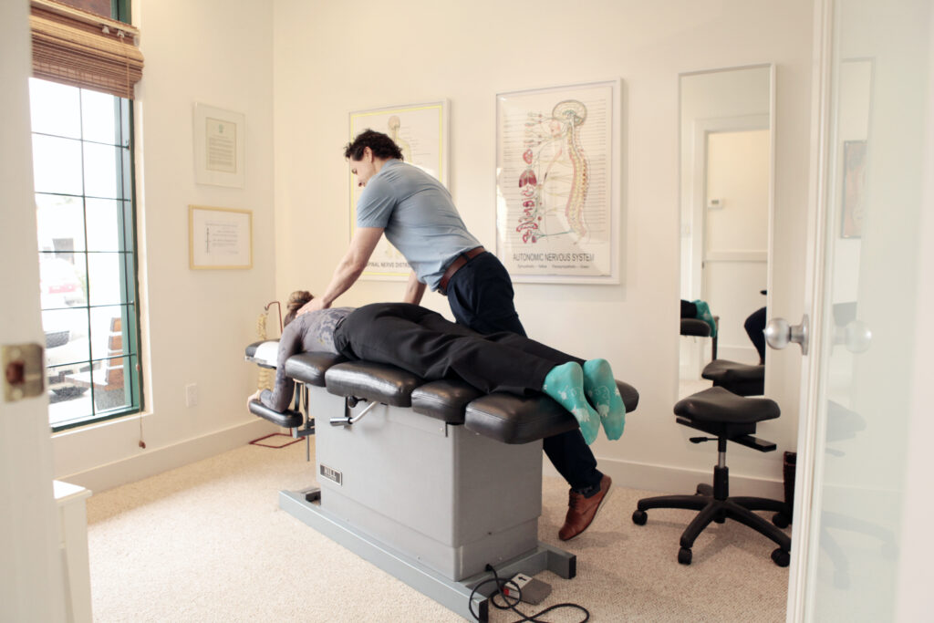 Skilled male chiropractor conducting a therapeutic chiropractic adjustment on a patient. The image captures the practitioner's concentration and technique, emphasizing his proficiency in chiropractic healthcare. Ideal for topics related to physical therapy, wellness, and non-invasive treatment methods